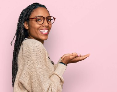 Afro-amerikan kadın, günlük giysiler içinde avuçlarını açıp fotokopi alanını gösteren, gülümseyerek mutlu bir şekilde gülümseyen. 