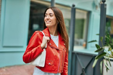 Genç İspanyol kadın gülümseyerek şehirde mutlu mesut dikiliyor..