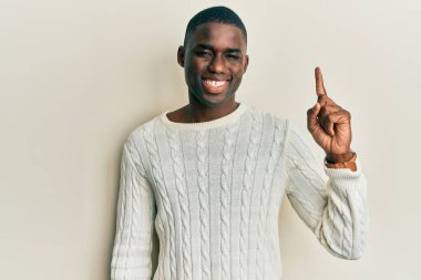 Gündelik giysiler giymiş genç Afro-Amerikan bir adam başarılı bir fikri işaret ediyor. Heyecanlı ve mutlu. Bir numara.. 