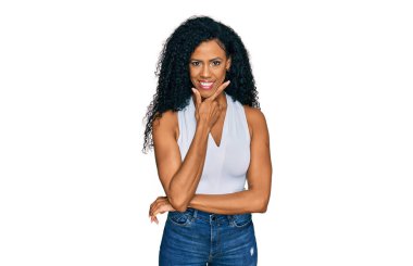 Orta yaşlı Afro-Amerikalı kadın kolsuz tişörtlü, gündelik giyinmiş kameraya kollarını kavuşturup gülümseyen ve çenesini kaldıran. Olumlu düşünmek. 