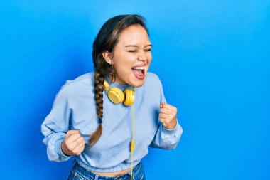 Kulaklıkla müzik dinleyen genç İspanyol kız kolları havada ve gözleri kapalı bir şekilde başarıyı kutluyor ve şaşırıyor. 