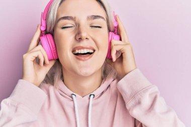 Genç sarışın kız müzik dinliyor kulaklıkla gülüyor ve gülüyor çünkü komik çılgın bir şaka.. 