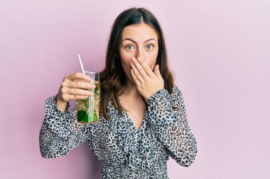 Genç esmer kadın mojito içiyordu. Ağzını eliyle kapatıyordu. Şok olmuştu ve hata yapmaktan korkuyordu. şaşırmış ifade 