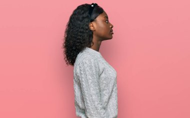 Beautiful african young woman wearing casual winter sweater looking to side, relax profile pose with natural face with confident smile. 