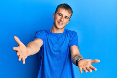 Günlük mavi tişört giyen, neşeli gülümseyerek yardım eli uzatan ve kabul gören beyaz bir genç.. 