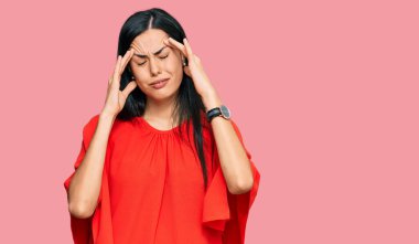 Güzel, genç bir kadın. Elleri başının üstünde, gündelik kıyafetler giyiyor. Stres yüzünden baş ağrısı çekiyor. migren ağrısı. 