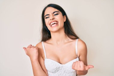 Brunette teenager girl posing elegant very happy and excited doing winner gesture with arms raised, smiling and screaming for success. celebration concept. 