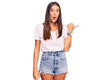 Gündelik beyaz t-shirt giyen genç İspanyol kadın elini yana doğru göstererek şaşırdı, ağzı açık hayret içinde kaldı.. 