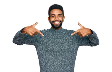 Genç Afrikalı Amerikalı sıradan kıyafetler giyen, kendine güvenen, yüzünde gülümseme olan, kendini gururlu ve mutlu gösteren bir adam.. 