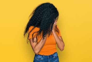 Orta yaşlı Afro-Amerikalı kadın, günlük kıyafetler ve gözlük takıyor ve ağlarken suratını ellerle kapatıyor. depresyon kavramı. 