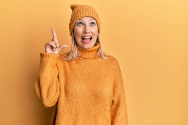 Orta yaşlı beyaz kadın yün kazak giyiyor ve şapkası başarılı bir fikri işaret ediyor. Heyecanlı ve mutlu. Bir numara.. 