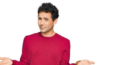 Gündelik giysiler giyen, kolları açık ve kafası karışık genç yakışıklı bir adam.. 