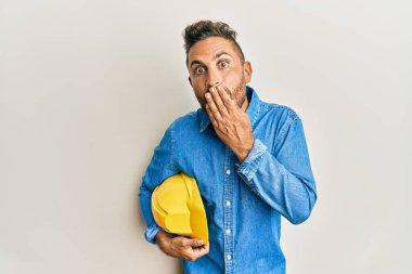 Sakallı, mimar şapkalı, ağzı ağızla kaplı yakışıklı bir adam. Şok olmuş ve hata yapmaktan korkuyor. şaşırmış ifade 