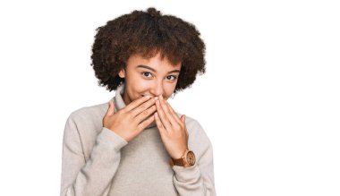 Kışlık yün kazak giyen genç İspanyol kız gülüyor ve utanıyor kıkırdıyor elleriyle ağzını kapatıyor, dedikodu yapıyor ve skandal konsepti yapıyor. 