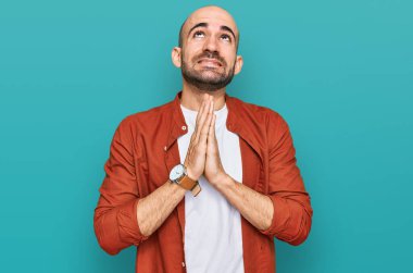 Gündelik giysiler giyen genç İspanyol adam elleri bağlı yalvarıyor ve dua ediyor. Yüzünde umut ifadesi var. Çok duygusal ve endişeli. Yalvarıyor. 