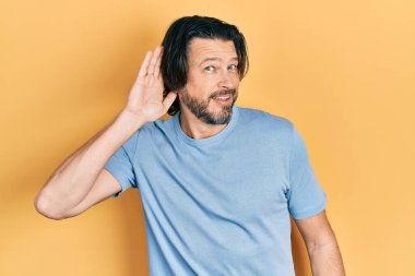 Orta yaşlı, günlük kıyafetler giyen, ağzı kulaklarında, dedikodu ve dedikodulara kulak misafiri olan beyaz bir adam. Sağırlık kavramı. 