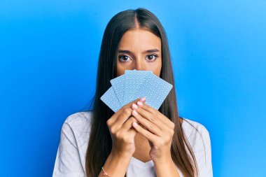 Genç İspanyol kadın poker oynuyor, yüzünü kartlarla kapatıyor. Depresyonda ve üzüntüden ağlıyor, ağlıyor ve korkuyor. hüzünlü ifade. 