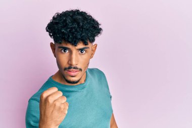 Genç Arap yakışıklı adam, rahat kıyafetler giyiyor kızgın ve kızgın yumruğunu kaldırıyor ve öfkeyle bağırıyor. öfke ve agresif konsept. 