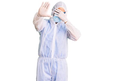 Doktor korumalı koronavirüs üniforması giyen genç İspanyol adam ve elleri ile gözlerini kapatan tıbbi maske ve hüzünlü ve korku ifadeleriyle jestleri durduruyor. utangaç ve olumsuz kavram. 