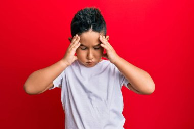 Küçük İspanyol çocuk gündelik beyaz tişört giyiyor. Baş ağrısı çekiyor. Acı ve migren yüzünden stresli. Eller başının üstünde.. 