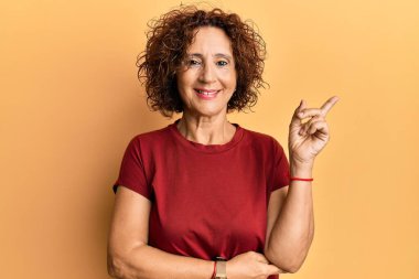 Güzel, orta yaşlı, sıradan kıyafetler giyen, mutlu bir şekilde gülümseyen, elleri ve parmakları yanda olan olgun bir kadın. 