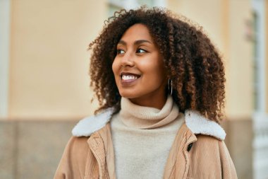 Genç Afrikalı Amerikalı kadın gülümseyerek şehirde mutlu mesut duruyor..