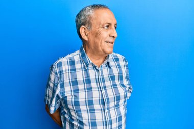 Latin kökenli üst düzey bir adam günlük giysiler giyiyor. Tarafını arıyor, profil pozu veriyor. Doğal bir yüzü ve kendine güvenen bir gülümsemesi var.. 