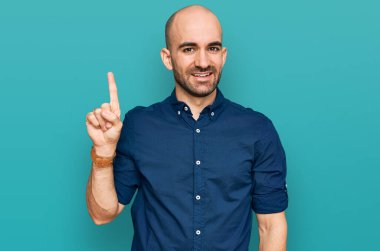 Gündelik kıyafetler giyen genç İspanyol adam başarılı bir fikirle işaret ediyor. Heyecanlı ve mutlu. Bir numara.. 