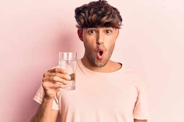 Mladý Hispánec Pije Sklenici Vody Vyděšený Ohromený Otevřenými Ústy Pro — Stock fotografie