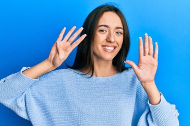 Gündelik kıyafetler giyen genç İspanyol kız dokuz numarayı gösterip işaret ederken kendinden emin ve mutlu bir şekilde gülümsüyor.. 