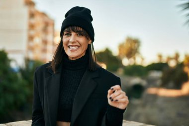 Genç İspanyol kadın gülümseyerek şehirde mutlu mesut dikiliyor..