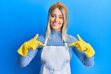 Güzel sarışın kadın daha temiz önlük ve eldiven giyiyor. Kendine güvenen, gülümseyen, kendini gururlu ve mutlu gösteren.. 