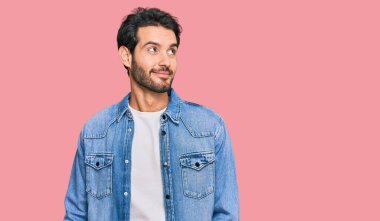 Gündelik kıyafetler giyen genç İspanyol adam gülümseyip yan tarafa bakıyor ve düşünüyor.. 