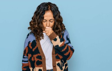 Orta yaşlı İspanyol kadın gündelik kıyafetler giyiyor kendini iyi hissetmiyor ve soğuk algınlığı veya bronşitin belirtisi olarak öksürüyor. sağlık hizmeti kavramı. 