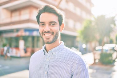 Genç İspanyol adam gülümseyerek şehirde mutlu bir şekilde yürüyor..