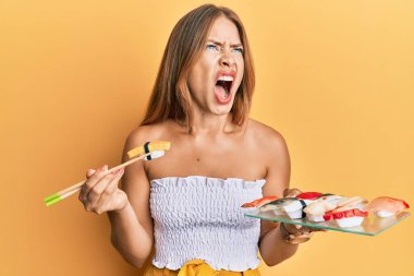 Güzel sarışın kadın omlet suşisi yiyor kızgın ve deli gibi bağırıyor öfkeyle bağırıyor, öfkeyle yukarı bakıyor.. 