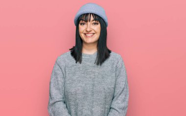 Yüzünde mutlu ve havalı bir gülümseme olan sevimli yün şapkalı İspanyol kadın. şanslı kişi. 