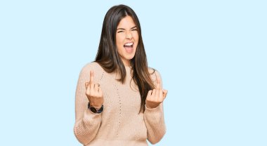 Young brunette woman wearing casual winter sweater showing middle finger doing fuck you bad expression, provocation and rude attitude. screaming excited 