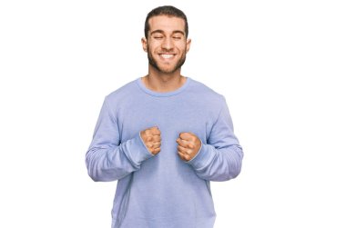 Başarı için heyecanlı, kolları havada, gözleri kapalı, sıradan kıyafetler giyen genç beyaz bir adam zaferi kutluyor. Kazanan konsept. 