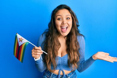 Zimbabwe bayrağı tutan genç İspanyol kız başarıyı mutlu bir gülümsemeyle kutluyor ve kazanan yüz ifadesi kaldırıyor. 