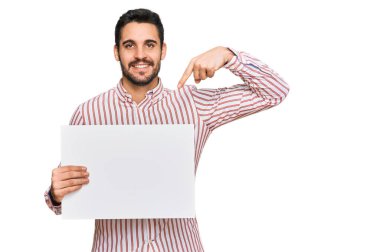 Boş pankart tutan genç İspanyol adam gülümseyen mutlu ve gururlu birini işaret ediyor. 