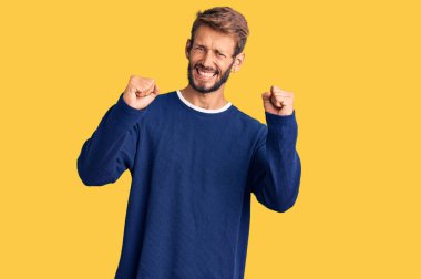 Sakallı yakışıklı, sıradan bir süveter giyen kızgın ve kızgın yumruk kaldıran sinirli ve öfkeyle bağıran bir sarışın. öfke ve agresif konsept. 