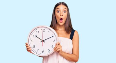 Genç İspanyol kadın büyük bir saat tutuyor. Korkmuş ve ağzı açık kalmış, şaşırmış ve şaşırmış. 