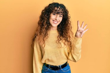 Latin kökenli genç bir kız günlük kıyafetler giyer ve parmaklarıyla dört numarayı gösterir.. 