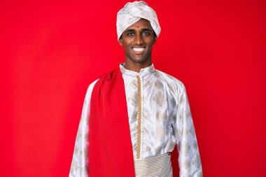 Geleneksel Sherwani sari giysileri giyen yakışıklı Hintli adam mutlu ve havalı bir gülümsemesi var. şanslı kişi. 