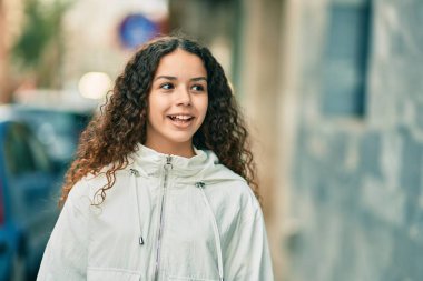 Hispanik genç kız gülümseyerek şehirde mutlu mesut duruyor..