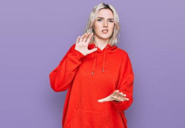 Gayri resmi giyinen genç sarışın kız tiksinti ifadesi takınıyordu. Tiksinti reaksiyonu yüzünden tiksinti ve korku ifadesi takınıyordu. Eller havada. 