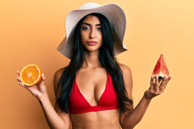 Karpuz ve portakal yiyen güzel İspanyol kadın yüzünde ciddi bir ifadeyle rahatlamış. Basit ve doğal bir şekilde kameraya bakıyorsun.. 