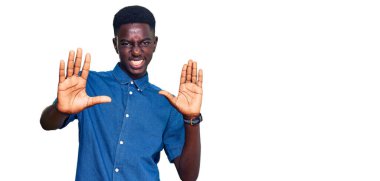 Gündelik kıyafetler giyen genç Afro-Amerikan adam avuç içi hareketlerini durduruyor, kızgın ve hayal kırıklığı ifadesi takınıyor. 