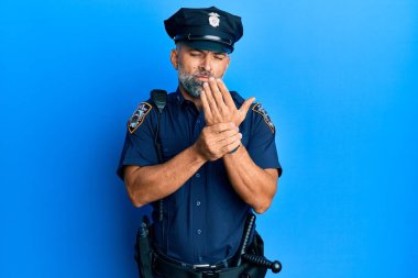 Polis üniforması giyen orta yaşlı yakışıklı bir adam ellerinde ve parmaklarında ağrı, eklem iltihabı. 